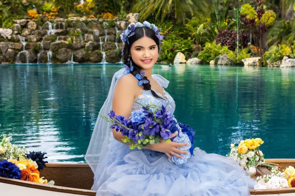 Chica con vestido azul de quince años posando en un bote decorado frente a una cascada