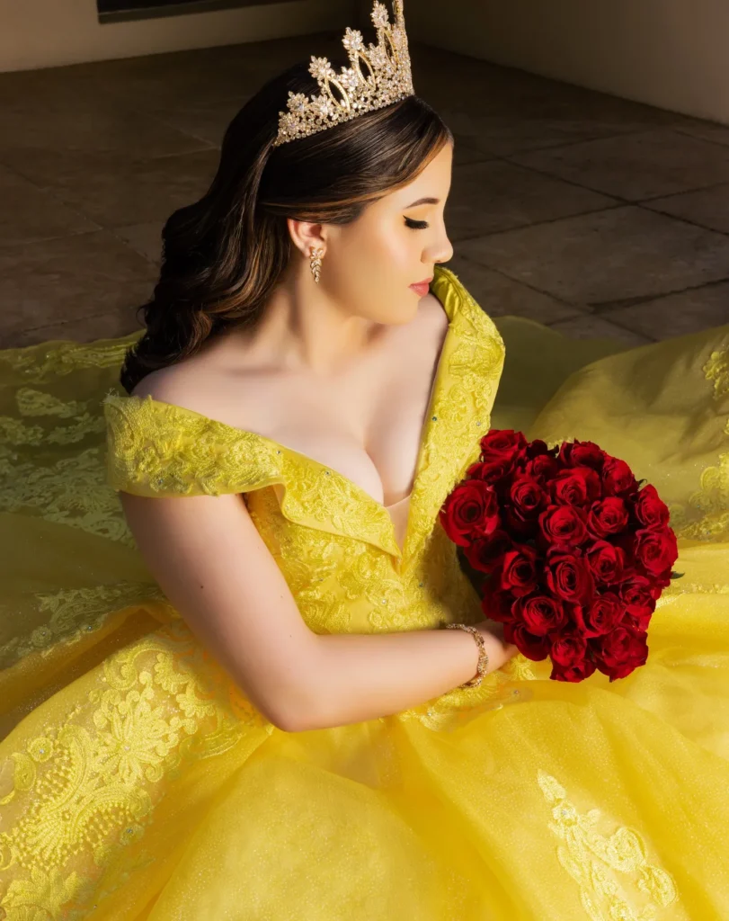 Quinceañera con vestido amarillo y corona, sosteniendo ramo de rosas