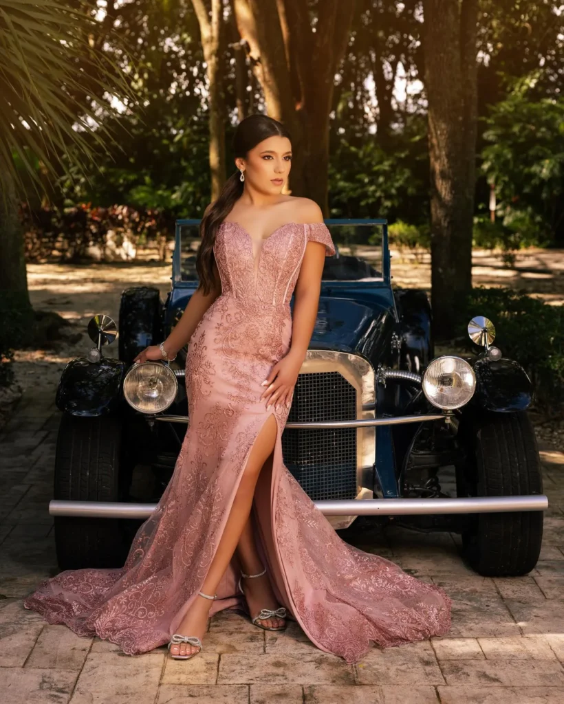 Quinceañera con vestido rosa elegante frente a coche antiguo
