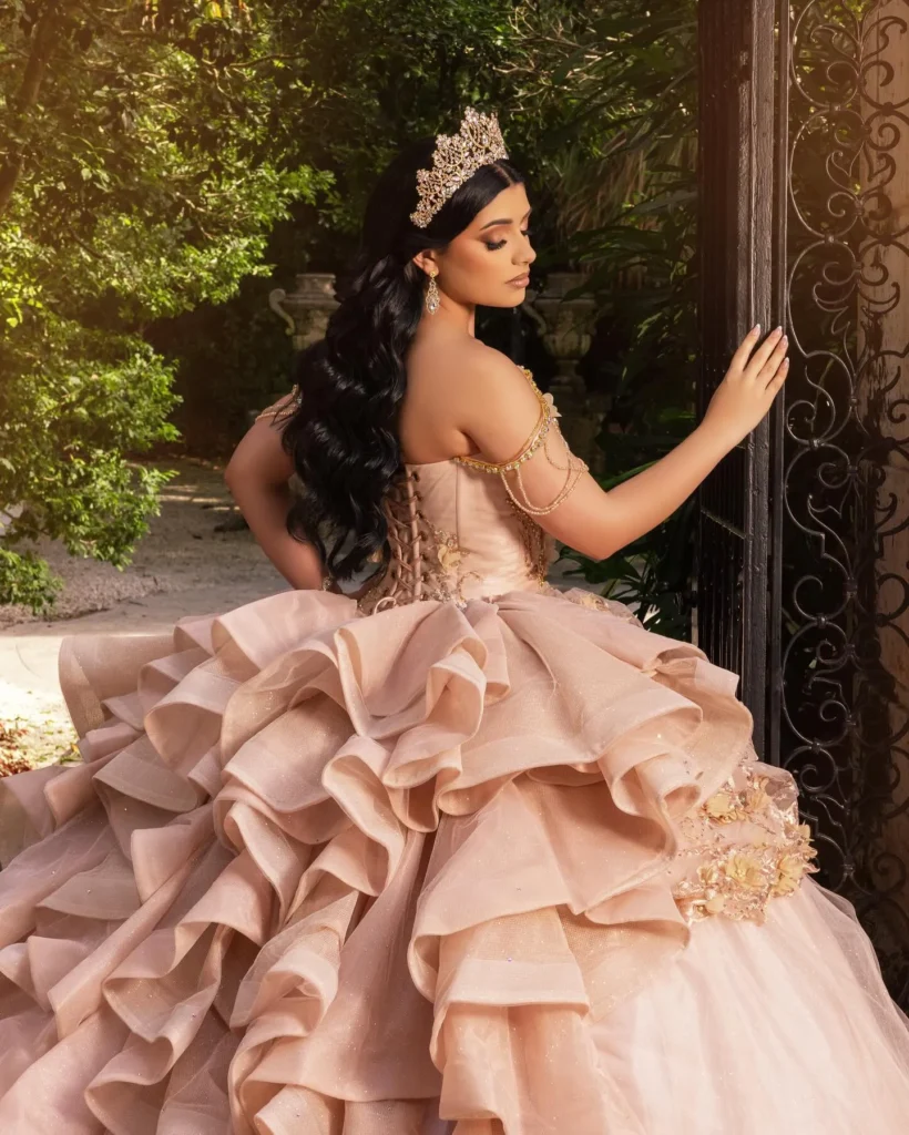 Quinceañera con vestido rosa champagne y falda de volantes en locación clásica